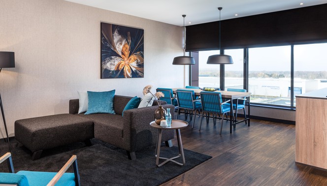 Woonkamer loft Van der Valk Hotel Veenendaal met bank, eettafel en uitzicht